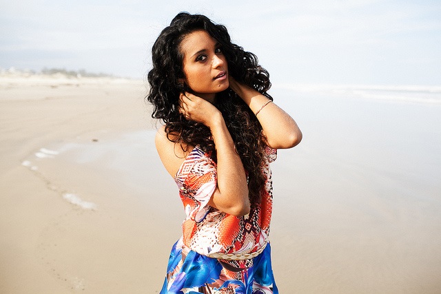 Schwarzhaarige Brasilianerin mit sommerlichem Kleid am Strand